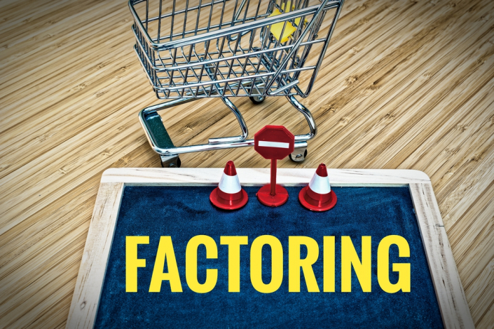 shopping cart with a blackboard, yellow letters say "factoring" with safety cones and sign