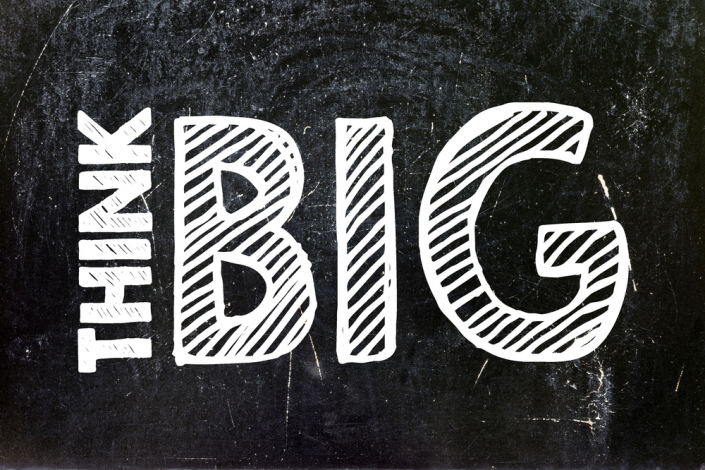 The words "think big" written in white on a black chalkboard background