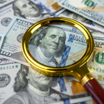 magnifying glass looking at $100 bill for fake money
